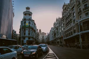 Evening view of traffic on Gran Via in Madrid with historic architecture and city lights.