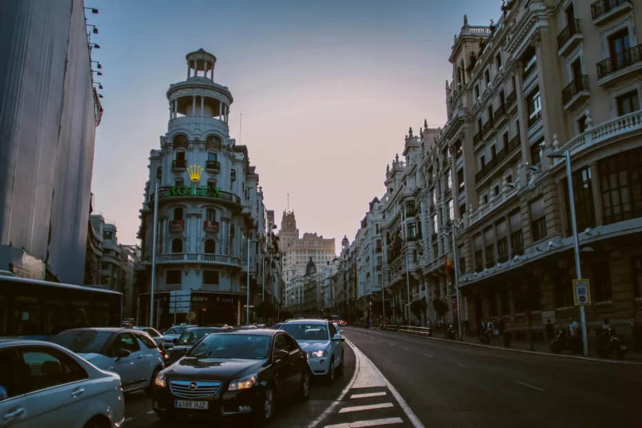 Evening view of traffic on Gran Via in Madrid with historic architecture and city lights.